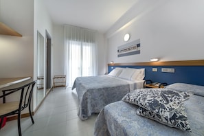 Habitación de hotel con dos camas, un escritorio y una silla.