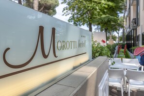 Un letrero de hotel con el nombre "Morotti hotel" y un adorno con flores rojas.