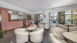 A modern hotel lobby with a bar area, seating arrangements, and a view of the outdoor patio. - Hotel Morotti (Misano Adriatico)