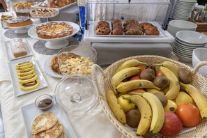 Un bufé con diversas opciones de pastelería, frutas y postres.