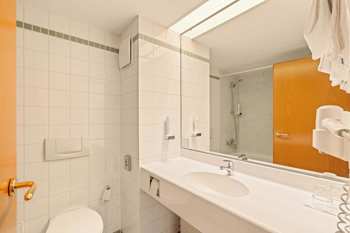 A bathroom with a white sink, mirror, and toilet.