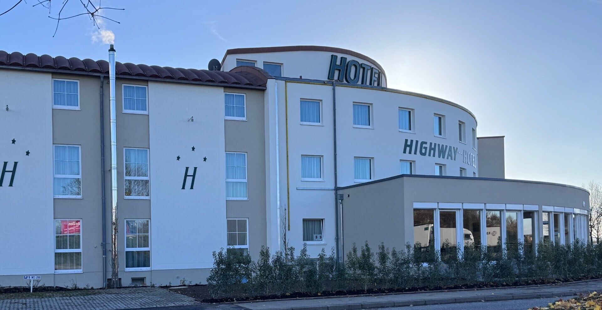 Ein Hotel mit zwei Etagen, einer gewölbten Fassade, zahlreichen Fenstern und einem Schild, das es als Highway Hotel kennzeichnet.