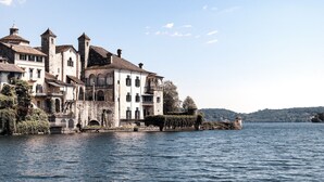 Un edificio histórico con múltiples torres y arcos, ubicado a orillas de un lago bajo un cielo despejado.