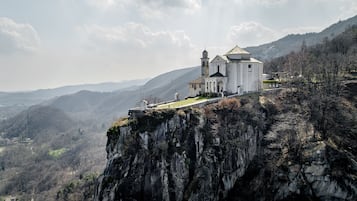 Une église blanche, dotée d’un clocher, se dresse sur une falaise surplombant une vallée.