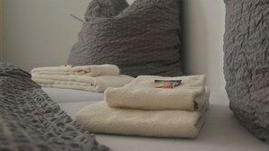 A neatly made bed with folded towels and two grey pillows. - Hotel Merlin (Cologne)
