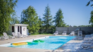 A swimming pool with lounge chairs, a lifeguard station, and trees in the background. - Domki  Polanki 23 (Wicko)