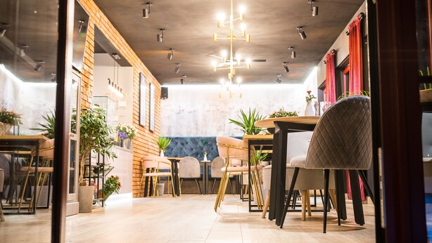 An interior with a dining area featuring a wooden table and chairs, potted plants, and a ceiling with hanging lights. - Domki  Polanki 23 (Wicko)