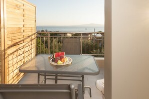 A balcony with a table set with fruits and a metal chair. - Elia & Thalassa (Kalamata)