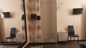 Habitación de hotel con un espejo grande, un minibar, un televisor y un sofá.