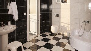 Un baño con suelo a cuadros blancos y negros, un lavabo blanco, un inodoro y una bañera.