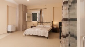 Un dormitorio con cama, mesitas de noche, un espejo, un radiador y una ventana con cortinas.
