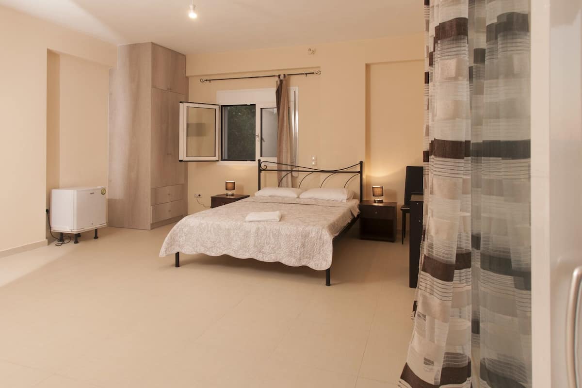 A bedroom with a bed, bedside tables, a mirror, a radiator, and a window with curtains.