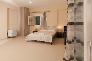 Un dormitorio con cama, mesitas de noche, un espejo, un radiador y una ventana con cortinas.