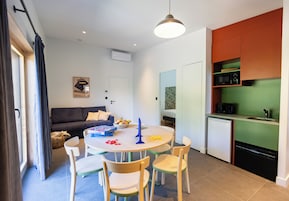 Un espacio habitable compacto con comedor, kitchenette y un sofá en la sala.