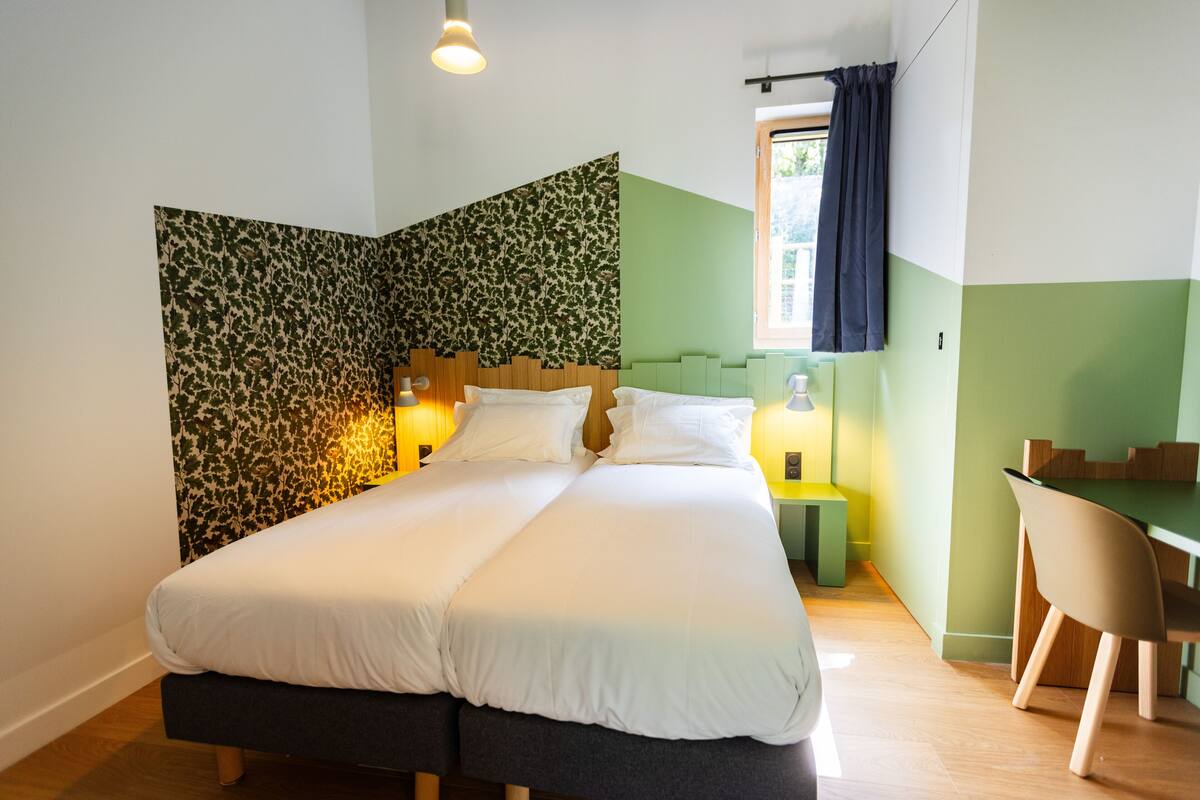 Een moderne slaapkamer met een groot bed, een bureau en een stoel.