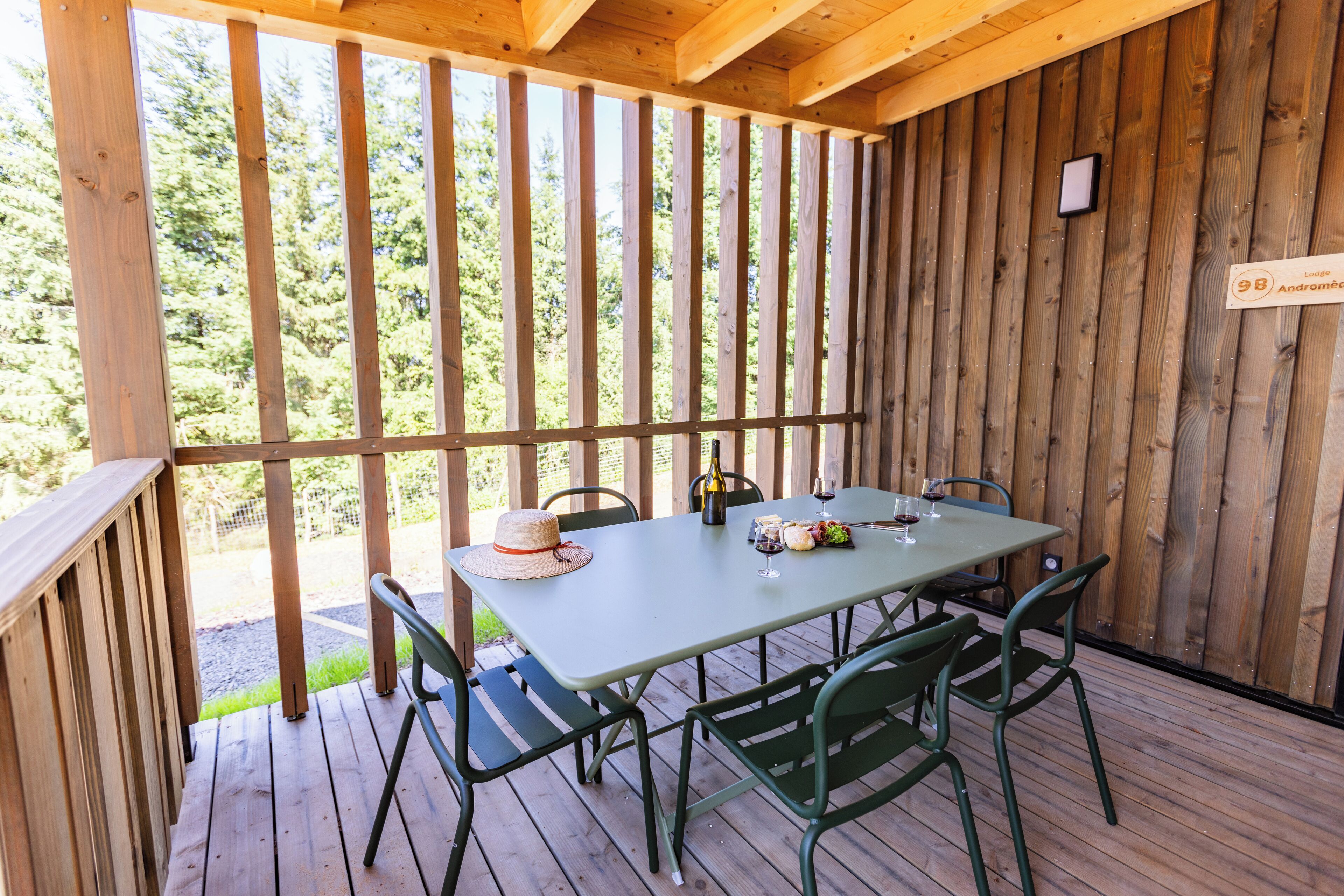 A wooden deck with a table and chairs, a bottle of wine, and a glass on the table.