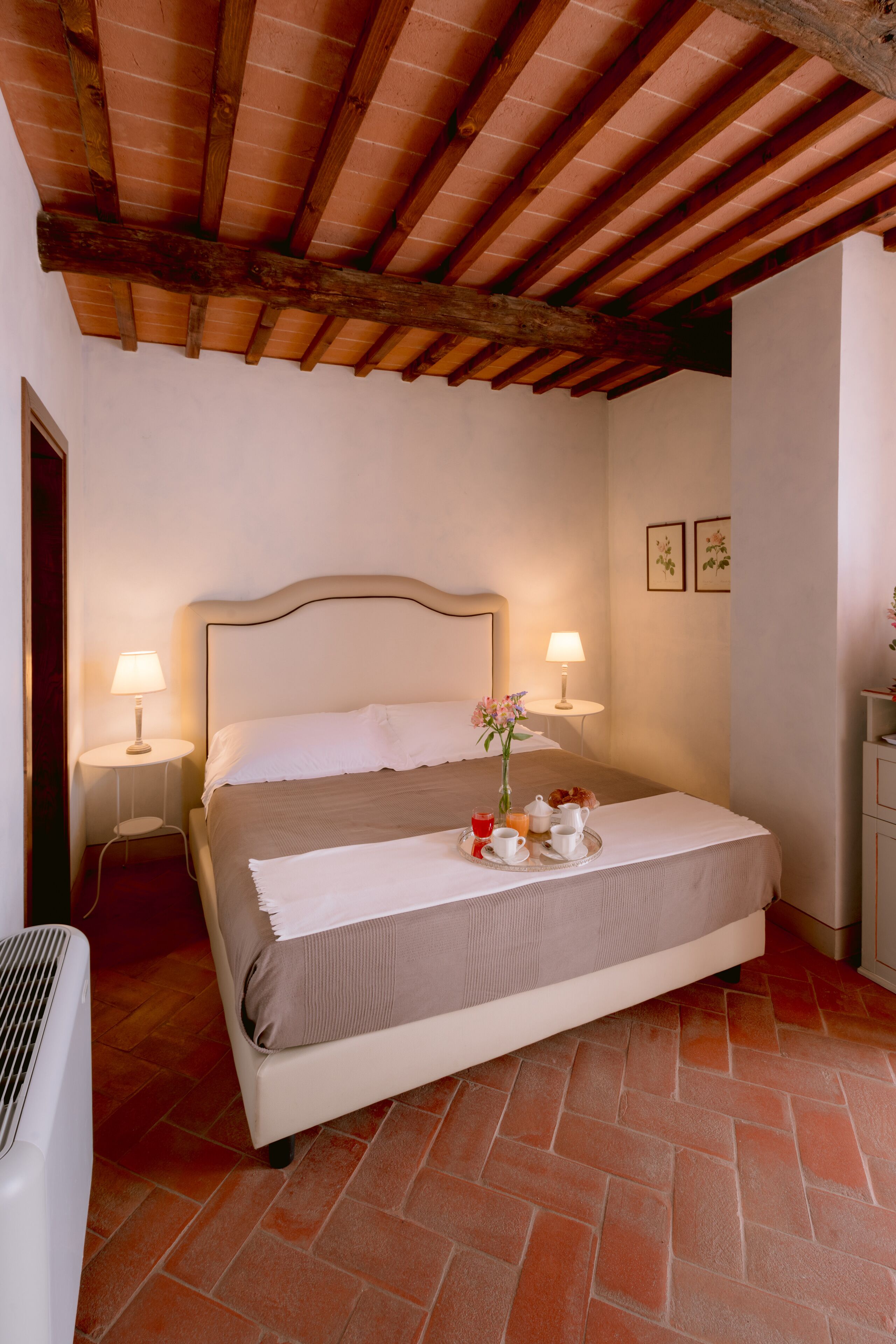 Una camera da letto con un letto, due comodini, un tavolo da notte, un termosifone e un soffitto in legno.