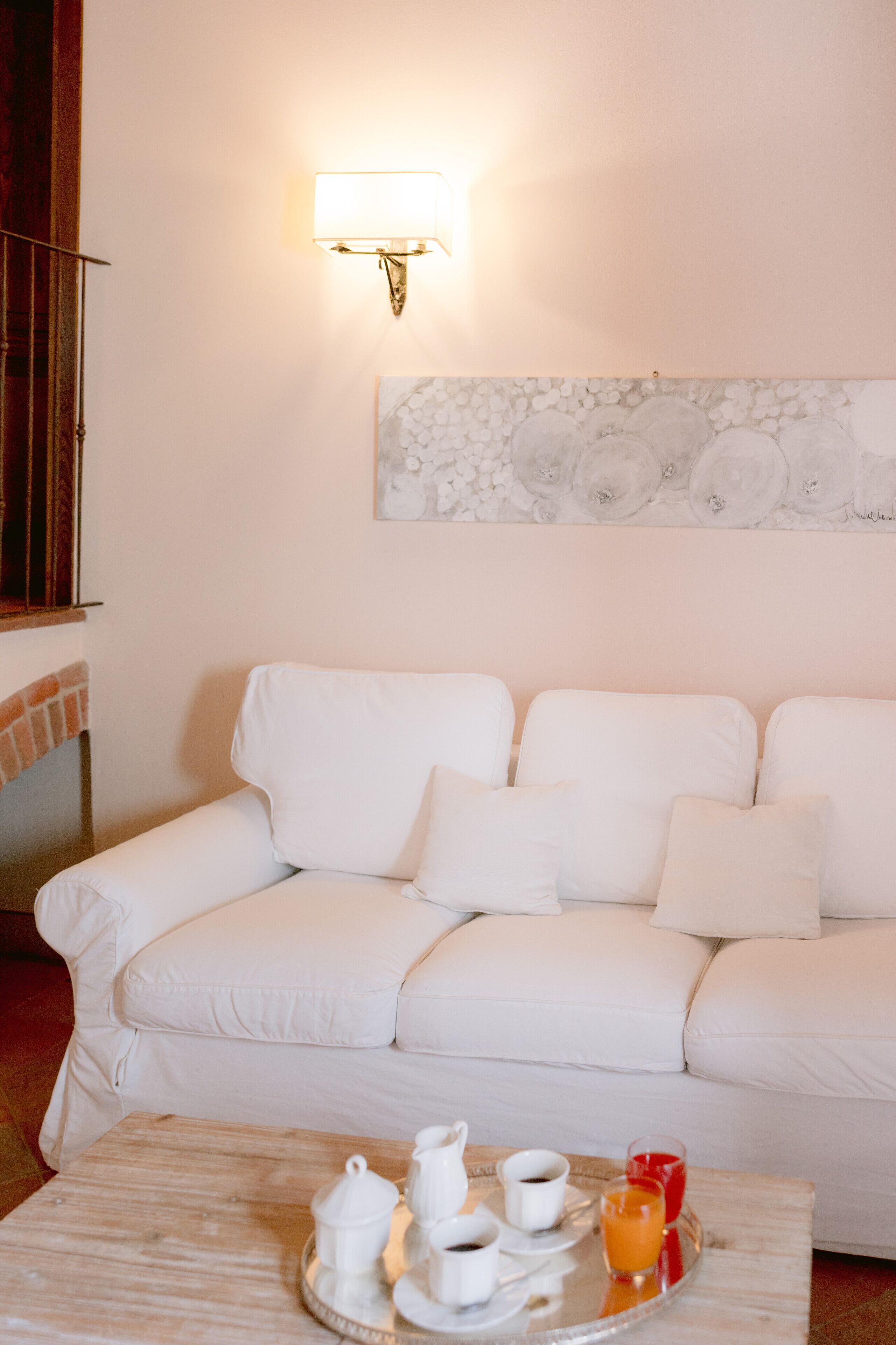 Un divano bianco con un vassoio di articoli per la colazione, una lampada a parete e un elemento decorativo a parete.
