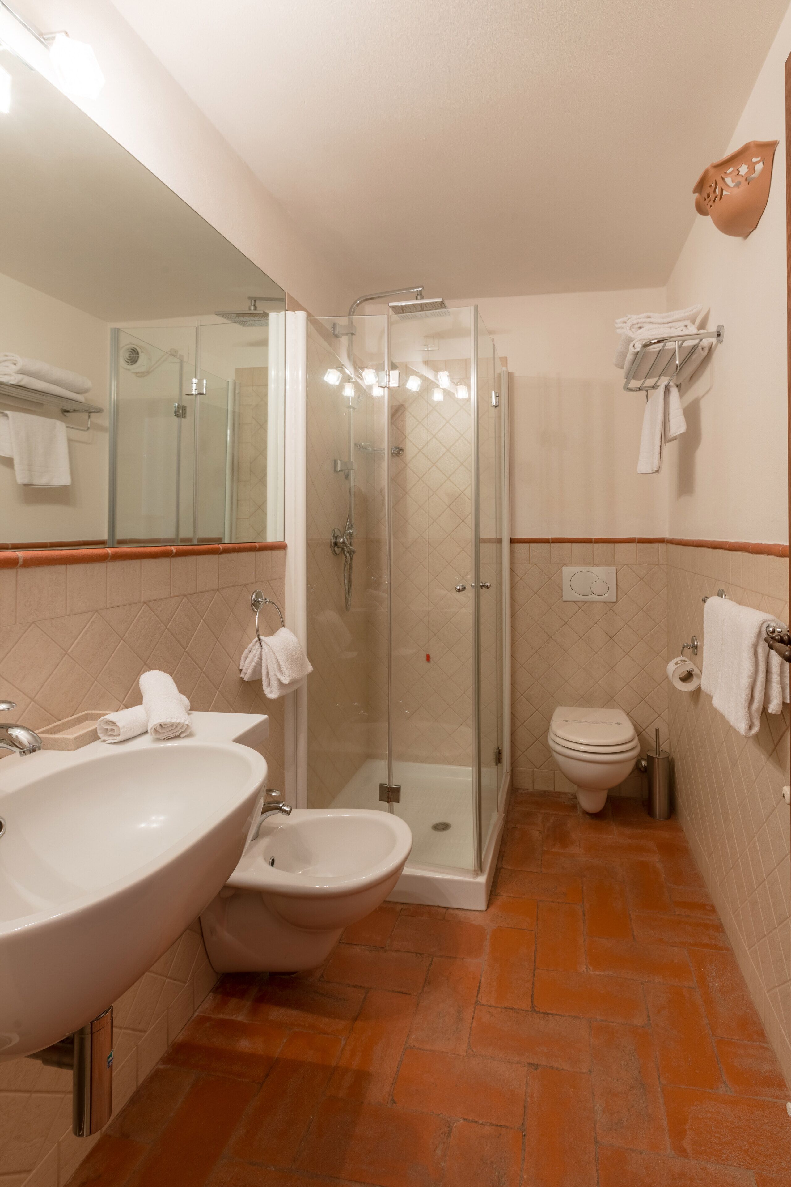 Bagno con lavandino, bidet, toilette e doccia in vetro.