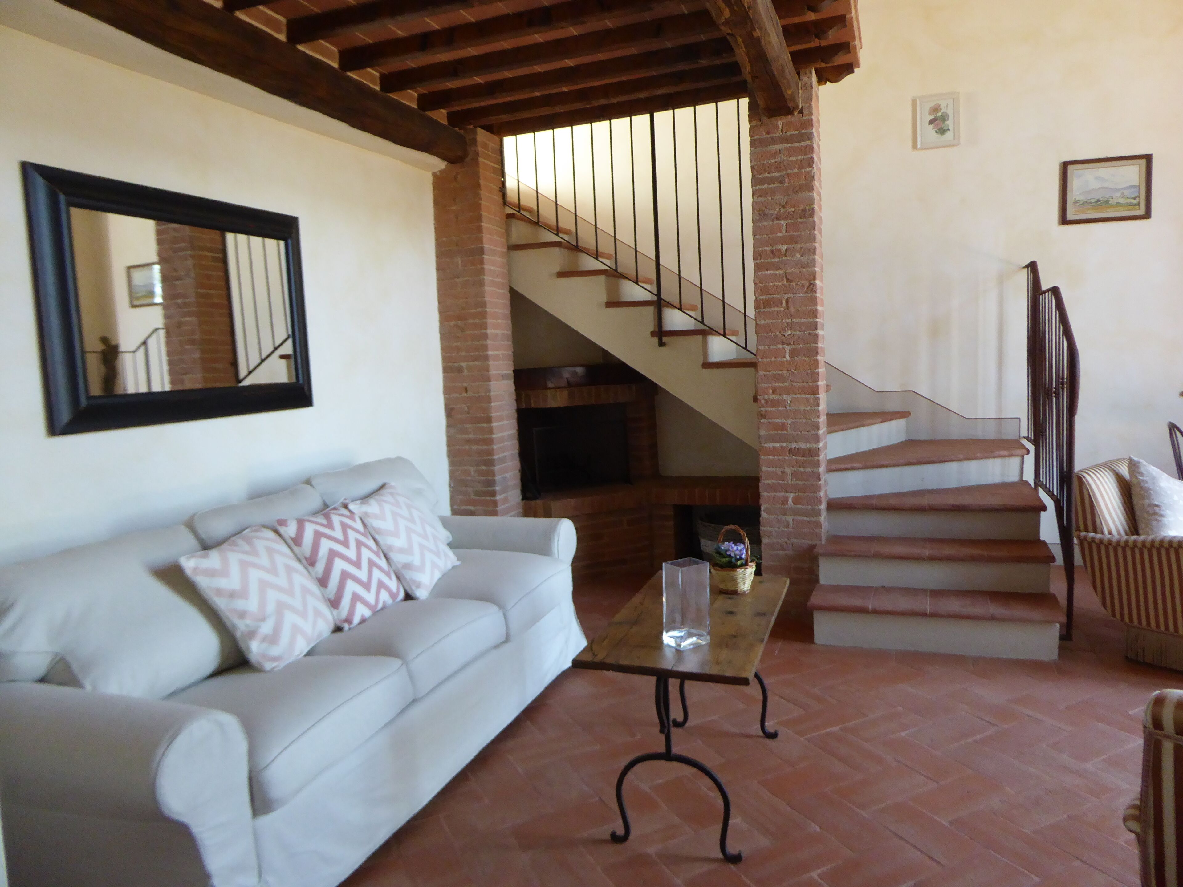 A living room with a sofa, a coffee table, a staircase, and a fireplace.