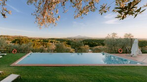 A swimming pool with a view of a hilly landscape, surrounded by trees and grass. - Borgo Sant'Ambrogio Resort (Trequanda)