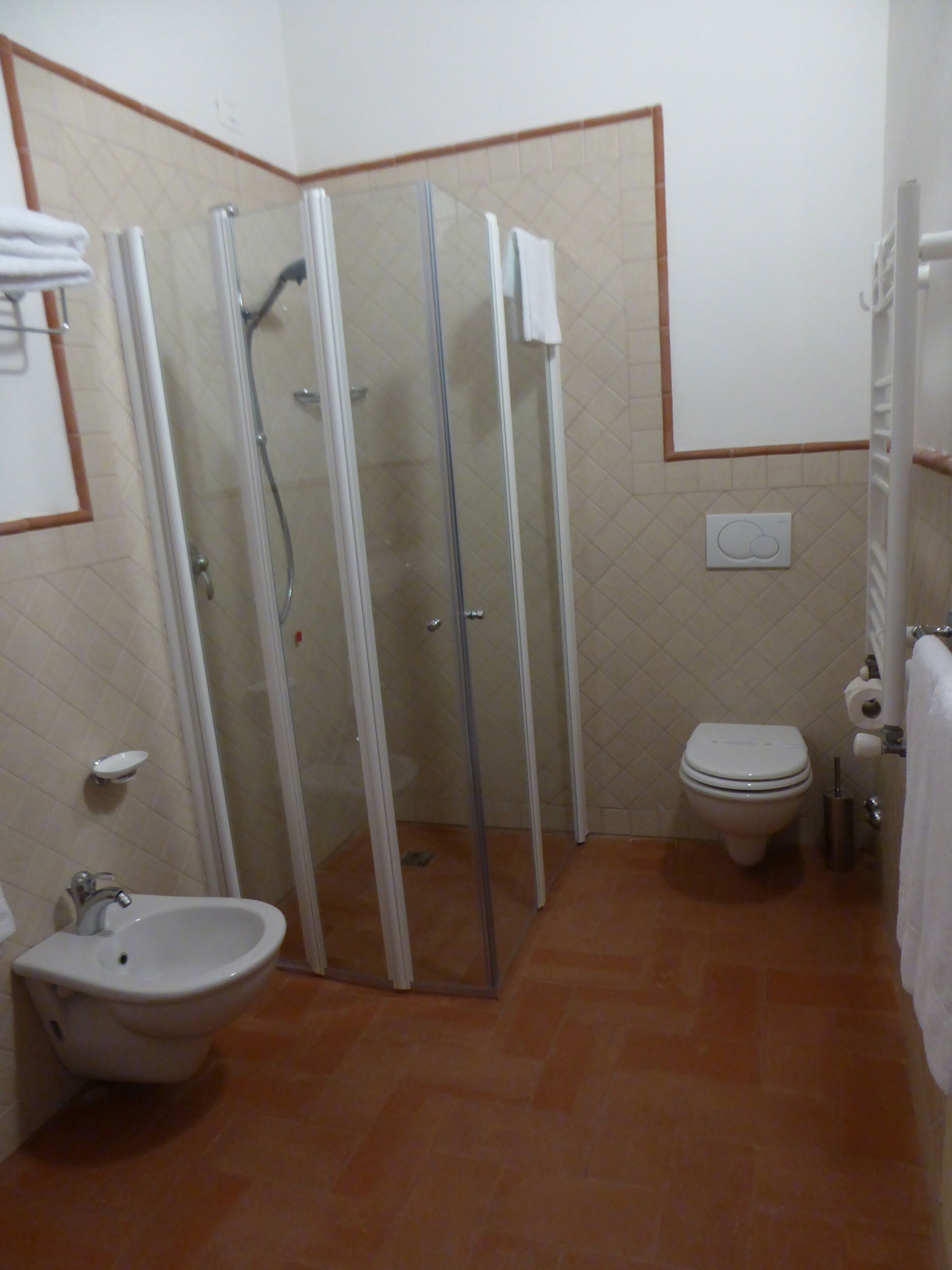 Un bagno con doccia in vetro, lavandino e water.