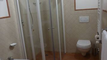 Un bagno con doccia in vetro, lavandino e water.