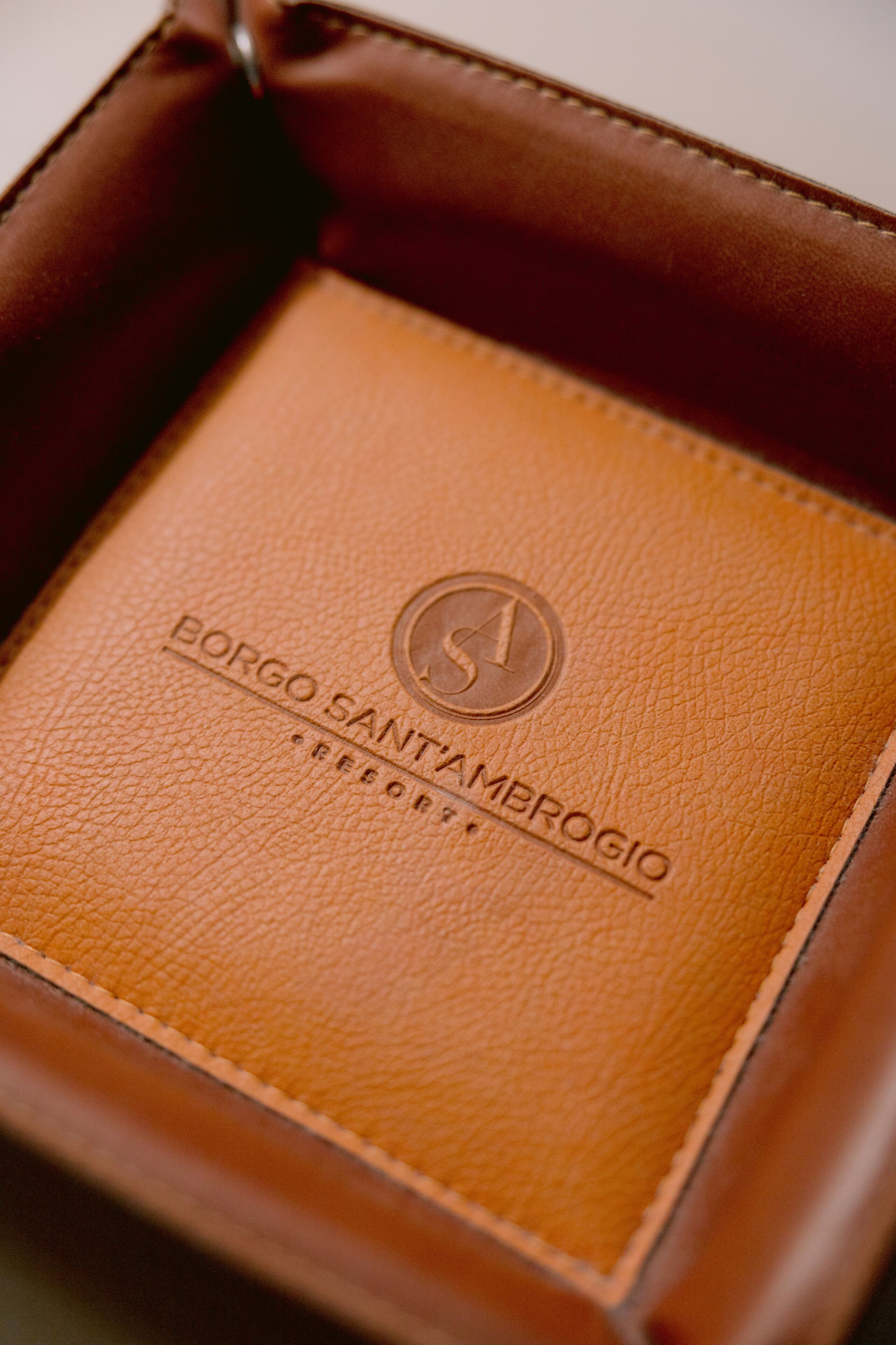 Una scatola di pelle marrone con testo a rilievo e un logo.