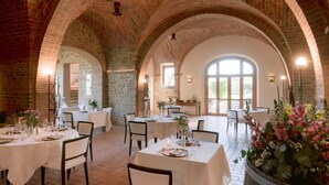 A restaurant with brick arches, white tablecloths, and floral centerpieces. - Borgo Sant'Ambrogio Resort (Trequanda)