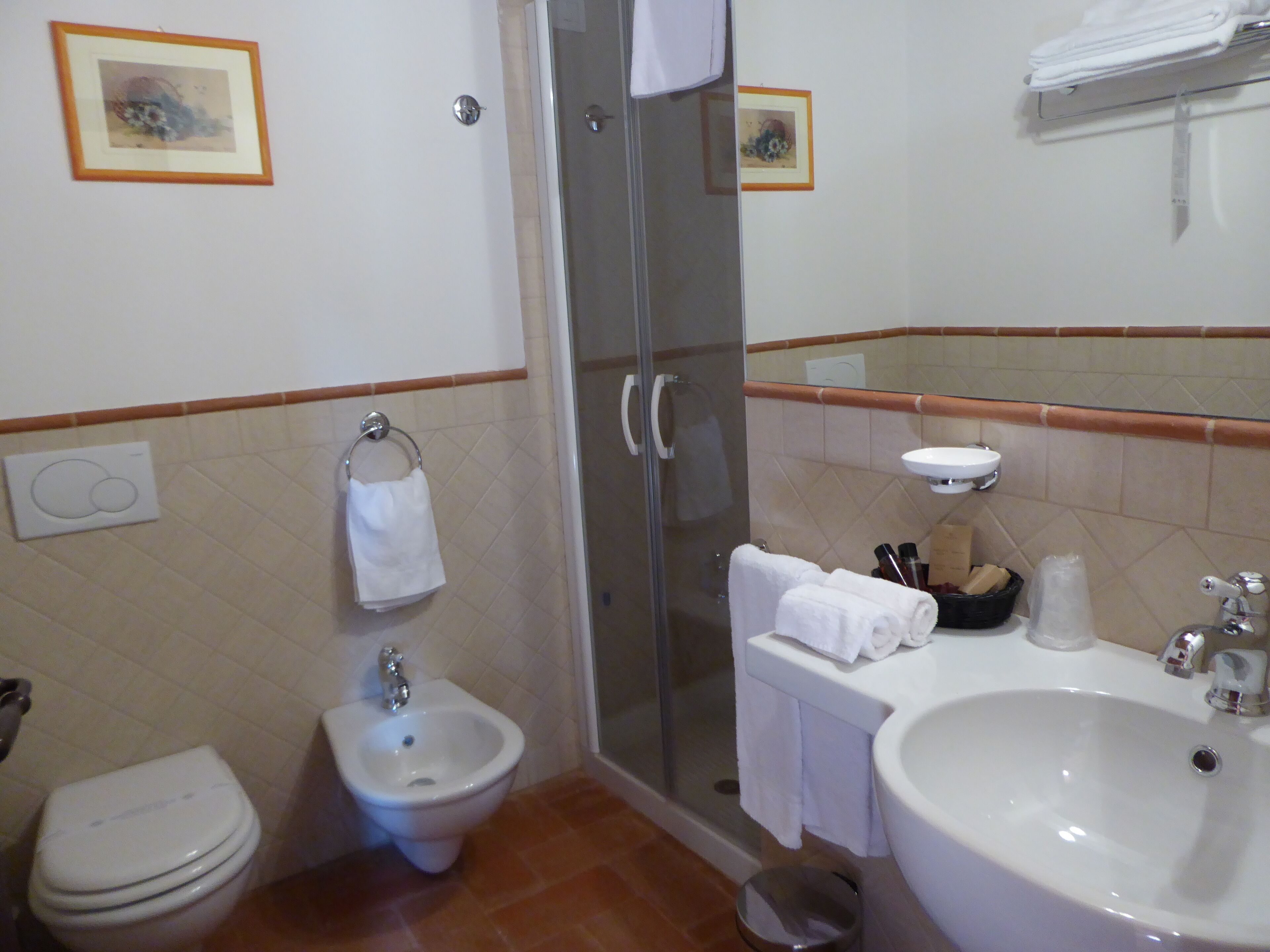 A bathroom with a toilet, bidet, shower, and sink.