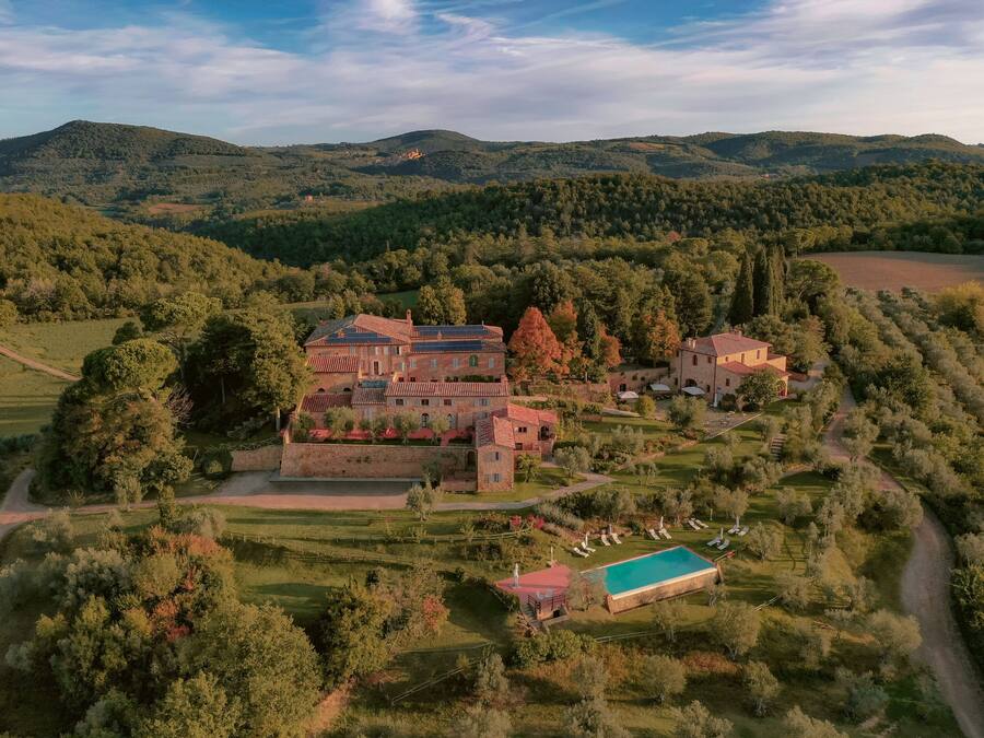 A large estate with multiple buildings, a swimming pool, and expansive green fields.