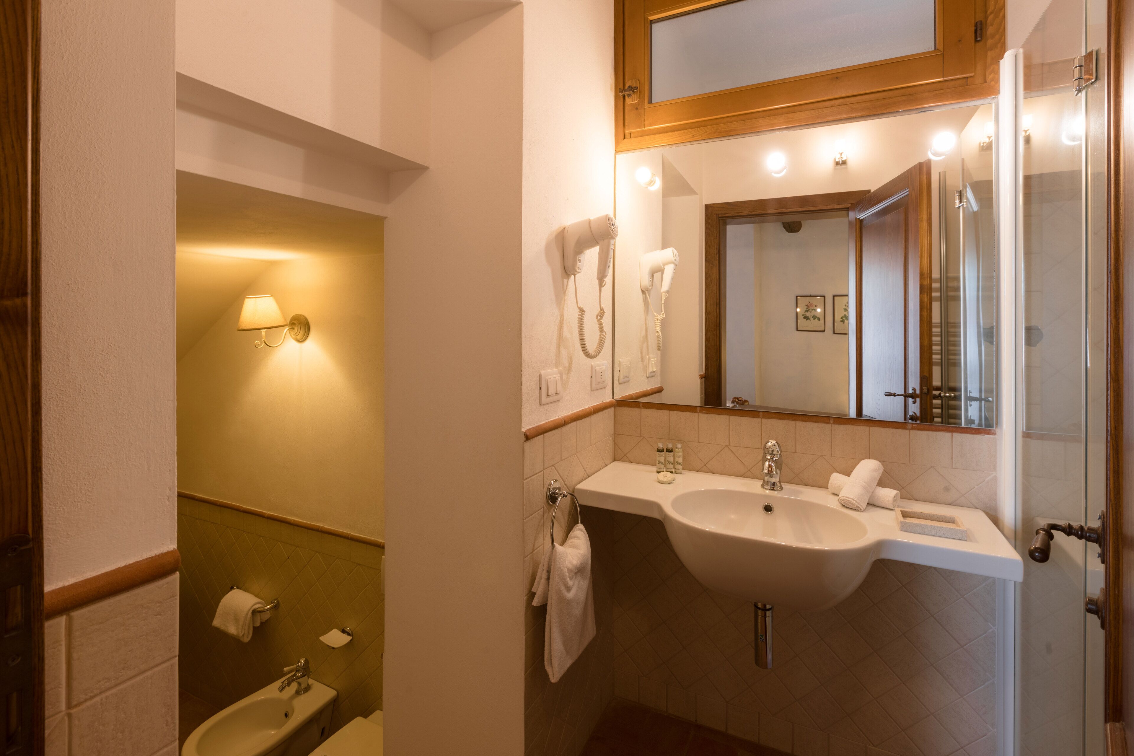 Un bagno con lavandino, specchio e portasciugamani.