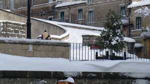 A snow-covered urban street with historic buildings, a stone wall, and a metal fence. - B&B La Rocca (Caprarola)