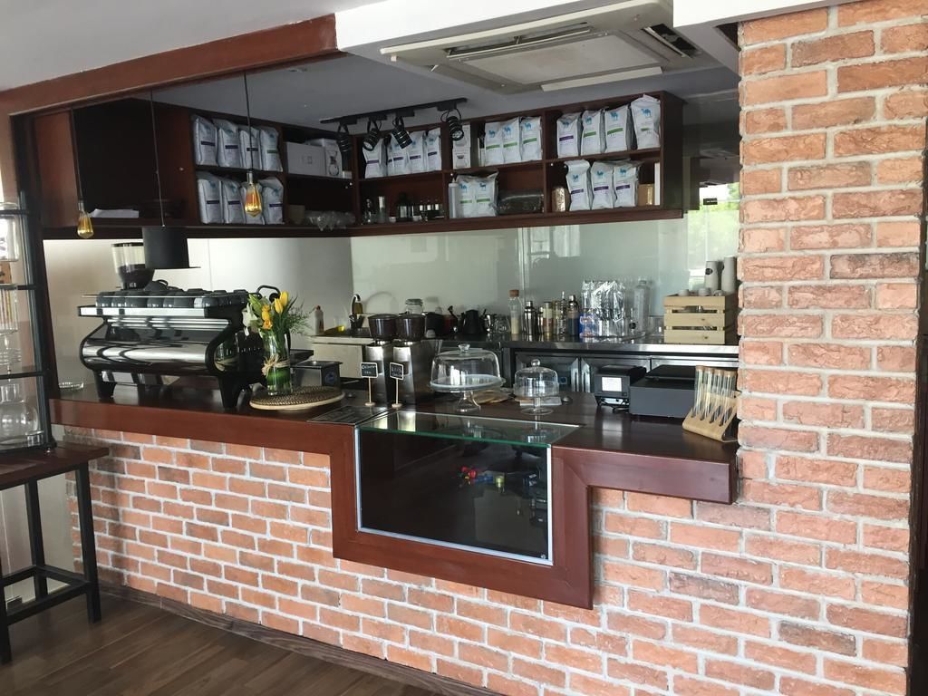 A kitchen with a brick wall, a glass counter, and shelves with bags.