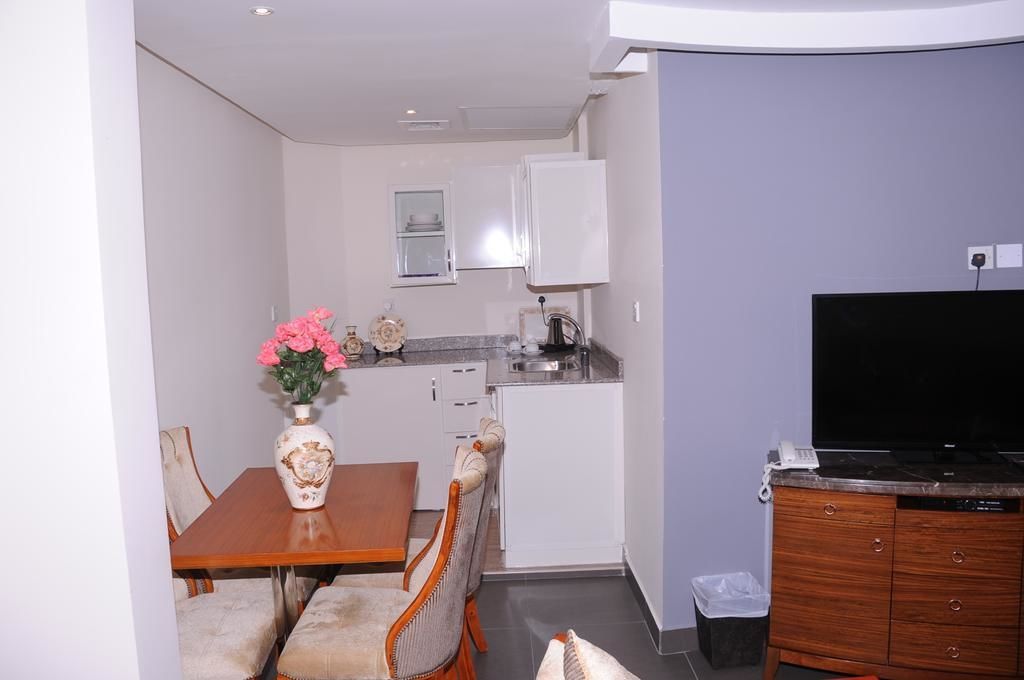 A compact living space with a dining area, kitchenette, and a flat-screen TV.