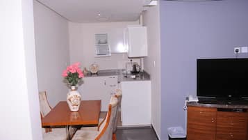 A compact living space with a dining area, kitchenette, and a flat-screen TV.