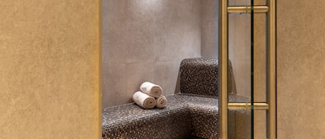 A modern bathroom with a textured bench, a glass partition, and a towel rack.