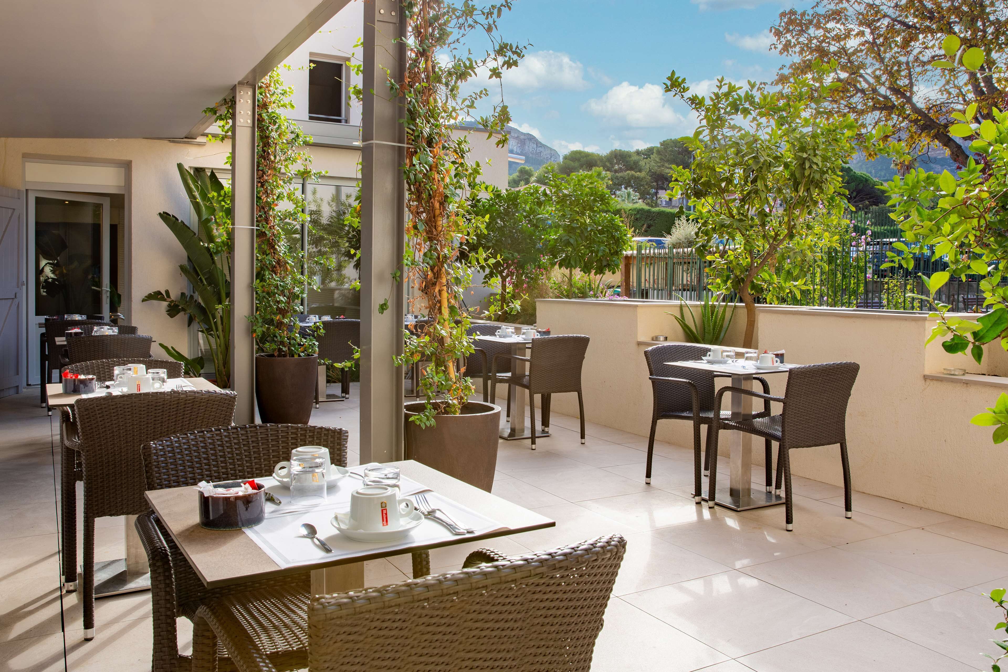 An outdoor patio with wicker furniture, potted plants, and a view of a mountain.