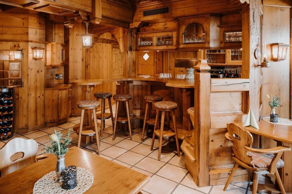 A wooden interior with a bar area, stools, and a dining table.