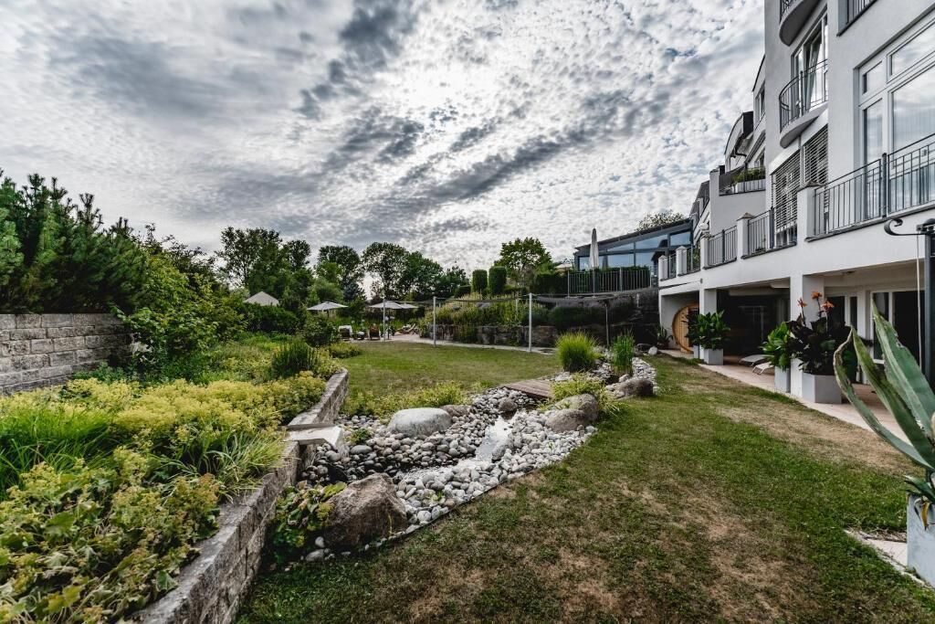Ein modernes Wohngebäude mit angelegtem Garten, einem gepflasterten Weg und blauem Himmel.