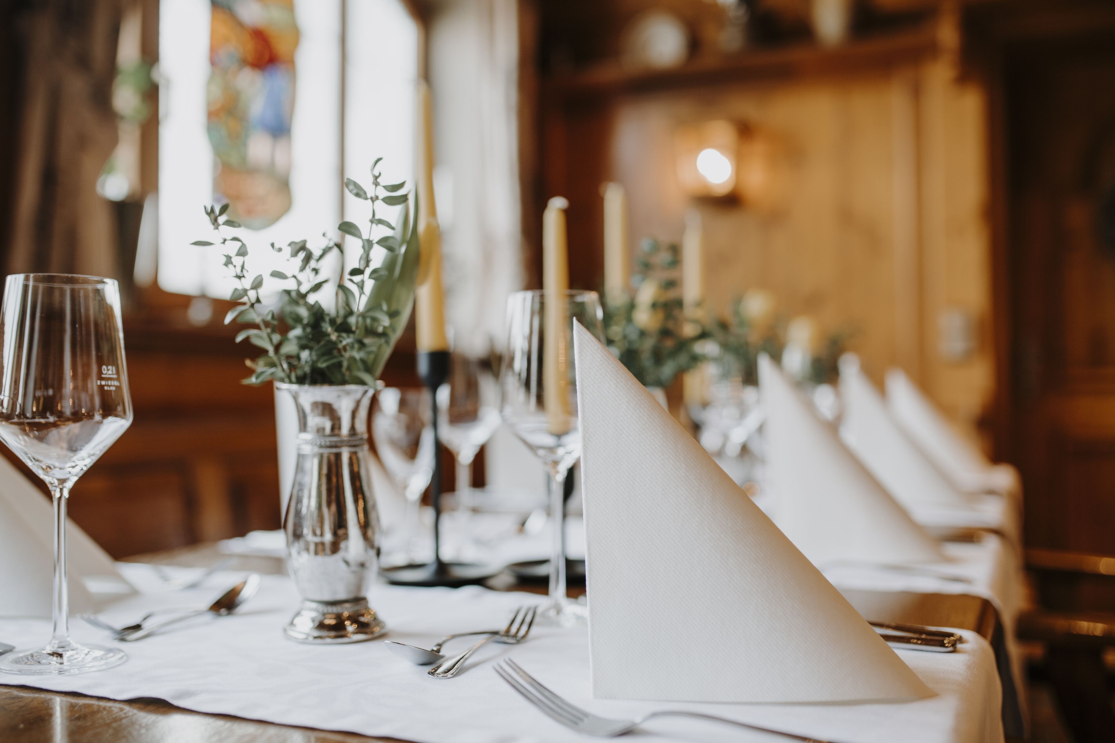 A table set for a formal dining experience with clear glassware, silverware, and a white napkin.