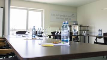 Una sala conferenze con un lungo tavolo, sedie, bottiglie d'acqua e un bicchiere.