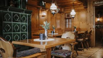 A wooden interior with a dining table, chairs, and a green cabinet.