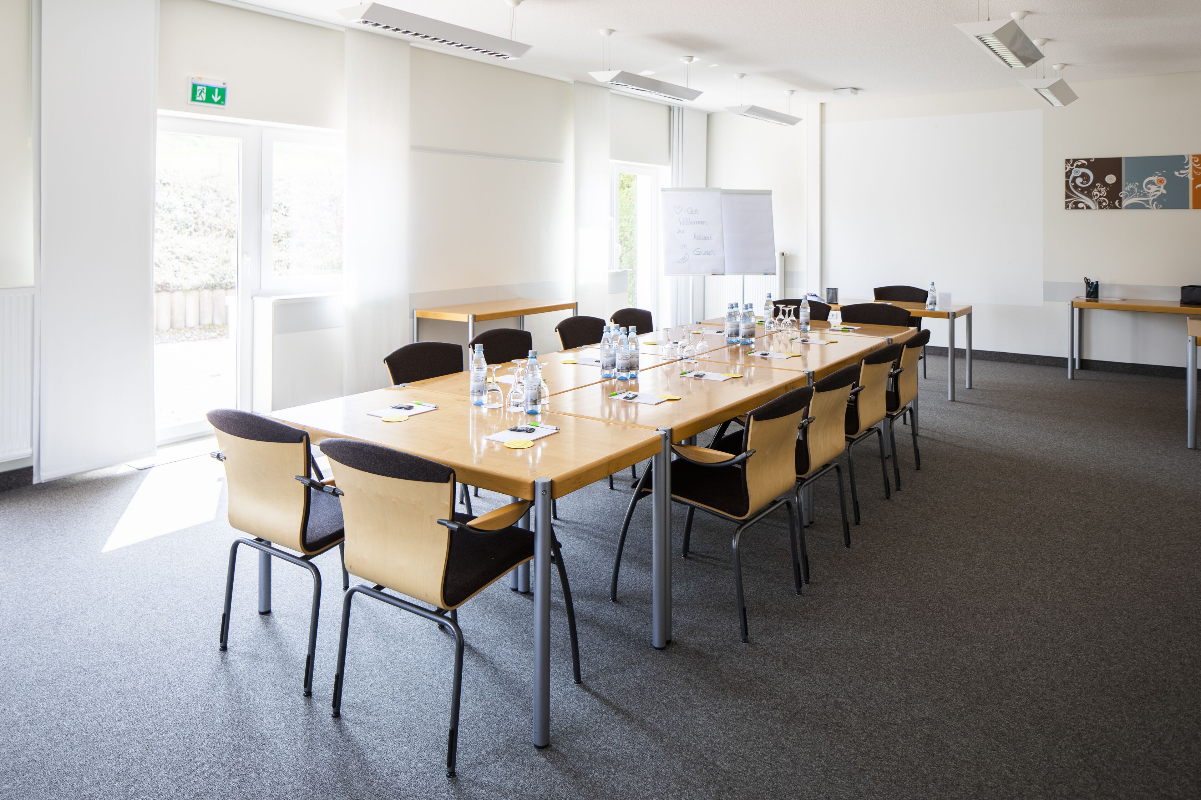 A conference room with a long table, chairs, a whiteboard, and a projector screen.