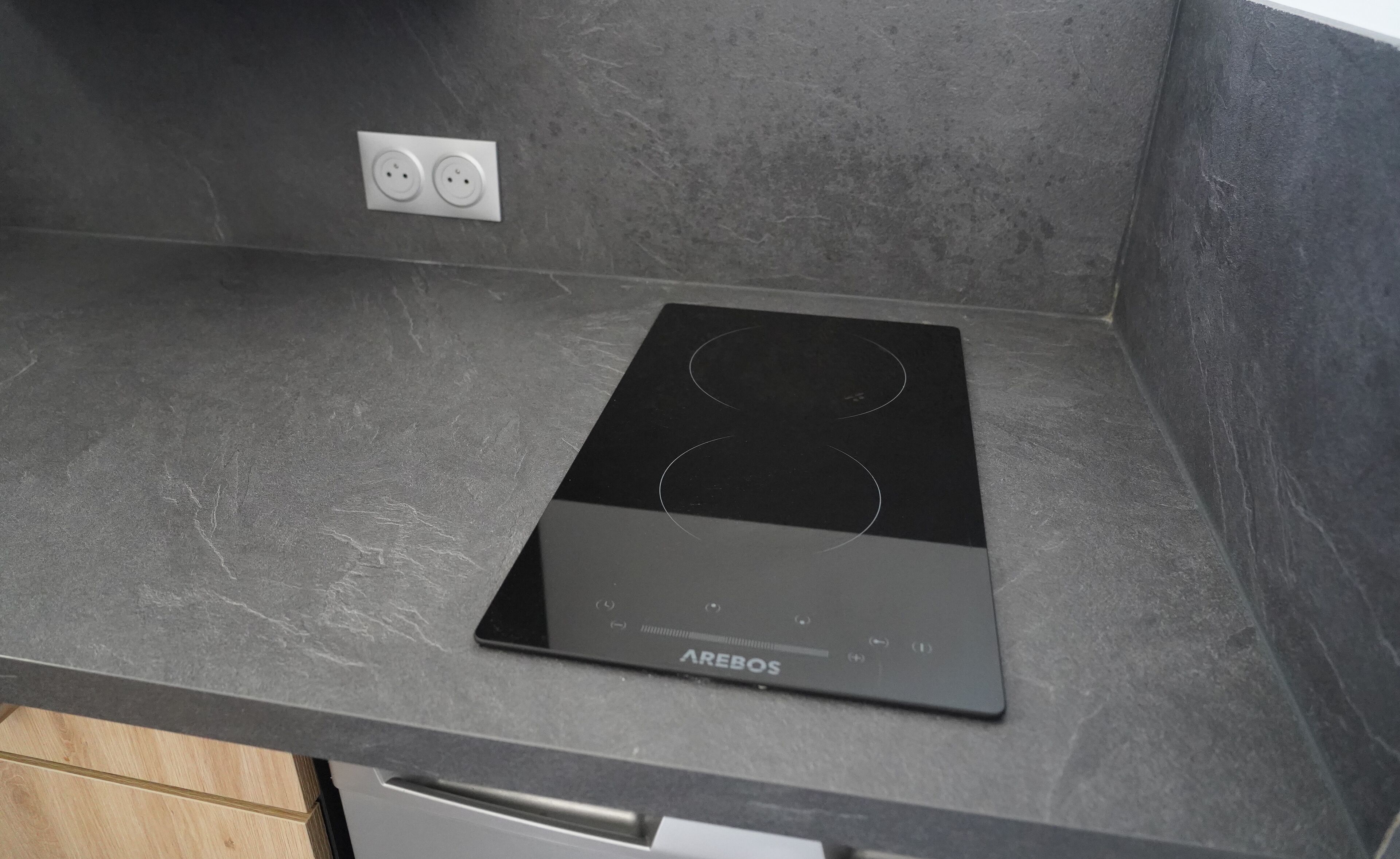 A black induction cooktop with the brand name AREBOS on a grey countertop.