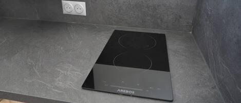 A black induction cooktop with the brand name AREBOS on a grey countertop.
