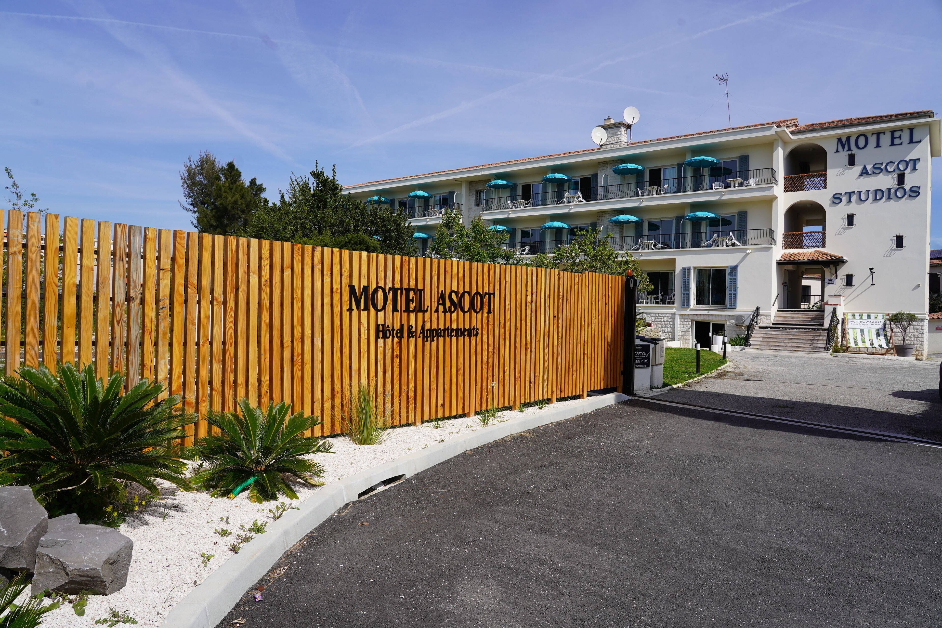 A two-story motel with balconies and a wooden fence in front.