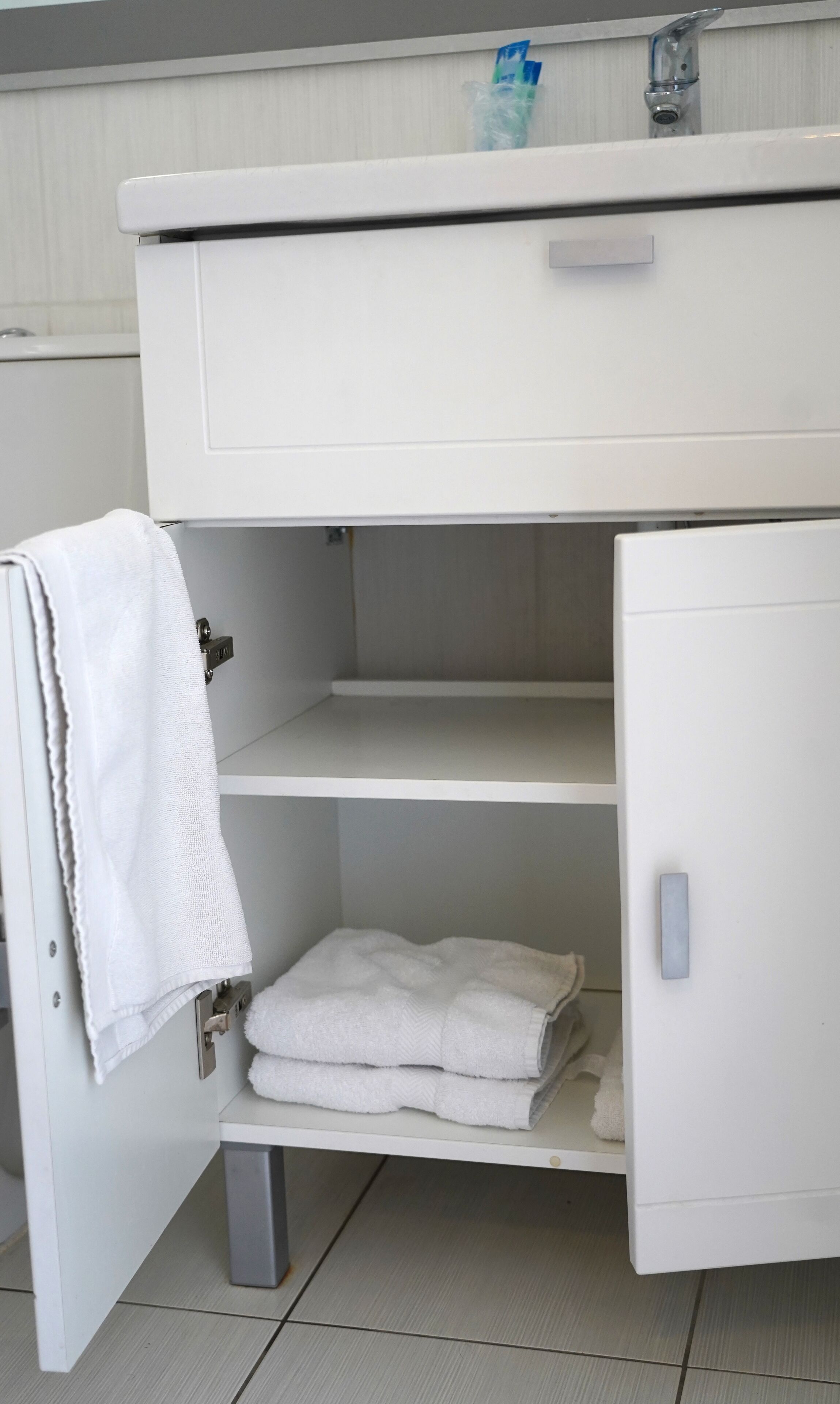 A white bathroom vanity with a towel rack, a sink, and a mirror.