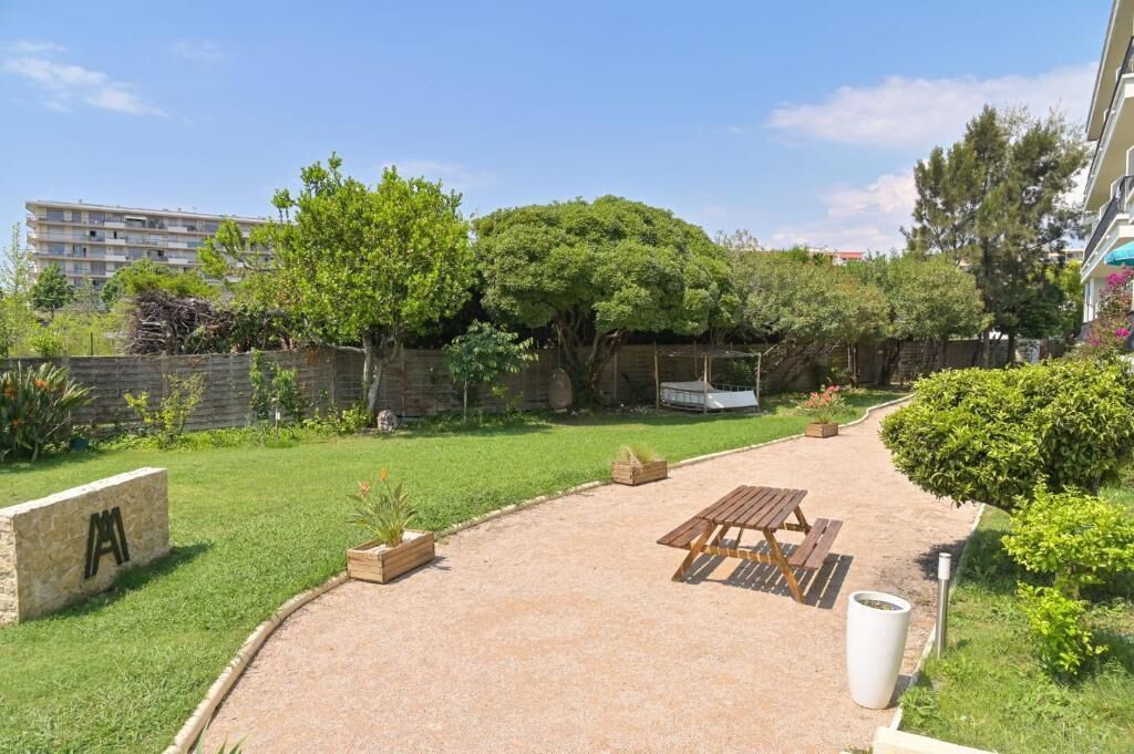 Un espacio exterior bien cuidado con una mesa de picnic, un banco de piedra y una jardinera grande.