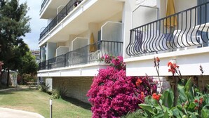 A multi-story building with balconies, a garden with pink flowers, and a clear sky. - MOTEL ASCOT - Hôtel & Appartements (Cagnes-sur-Mer)